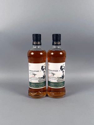 deux bouteilles de whisky posées l'une à côté de l'autre sur une surface grise