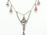 a necklace and earring set with pink stones on a mannequin