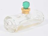 une petite bouteille en verre avec un bouchon vert posée sur une surface blanche
