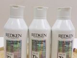 three bottles of redken hair products sitting on a table