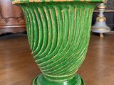 un vase vert contenant des fleurs, posé sur un parquet