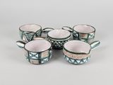 quatre tasses avec des anses et une poignée sont posées sur une table