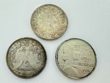 three different types of coins sitting on top of a white surface