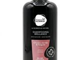 une bouteille de shampoing noire avec une étiquette rose