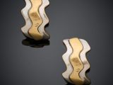 une paire de boucles d'oreilles en or et en argent posées sur un fond noir