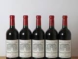 six bouteilles de vin sont posées sur une table en bois devant un mur blanc