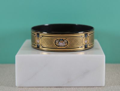 a close up of a black and gold bracelet on a marble block