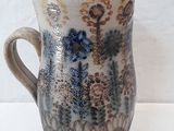 a picture of a ceramic pitcher with a floral design on it
