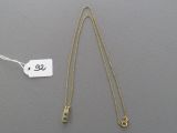 un collier en or orné d'une pierre verte et muni d'une étiquette de prix