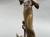an antique bronze statue of a woman holding a bird on a marble base