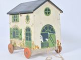 a small wooden toy house with a green door and windows