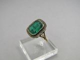 a close up of a ring with a green stone in it