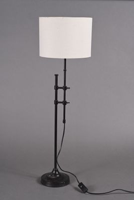lampe sur pied avec un abat-jour blanc monté sur un pied noir et un corps de lampe cylindrique blanc