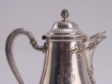 an antique silver plated coffee pot with a handle on a table