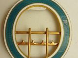 a blue and gold brooch with a boat on it