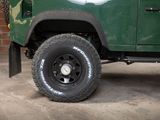 an image of a green jeep parked in front of a brick wall