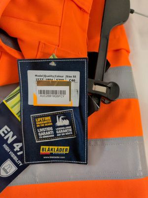 un gilet de sécurité orange muni d'une étiquette nominative et une paire de ciseaux