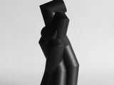 une sculpture noire posée sur une table près d'un mur blanc