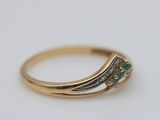 a close up of a gold ring with two emerald stones
