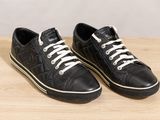 black leather sneakers with white laces on top of a wooden table