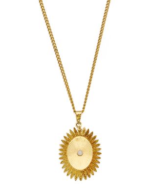 a gold necklace with a sunburst pendant on a chain