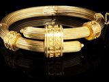 gros plan d'un bracelet en or sur une surface noire