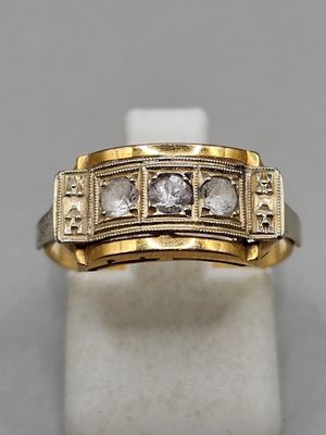 a close up of a gold and diamond ring on a white surface