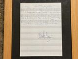 a framed photograph of a piece of music paper with a handwritten note