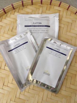 trois paquets de masques pour le visage posés sur un plateau en bambou