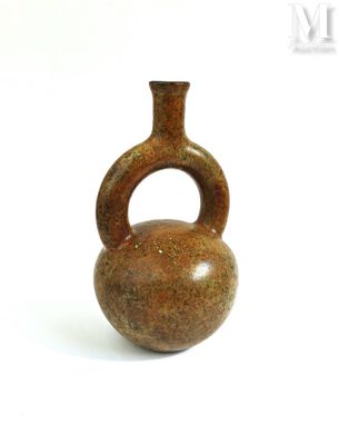un petit vase marron muni d'une anse, posé sur une surface blanche