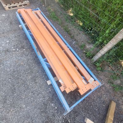 a wooden bench on the ground next to a wire fence