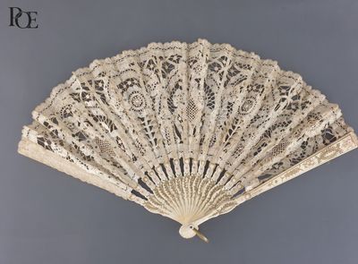 un éventail en dentelle blanche avec un manche en bois sur fond gris