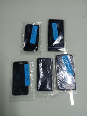 four cell phones are wrapped in plastic bags on a table