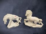 two white ceramic figurines of horses on a blue background