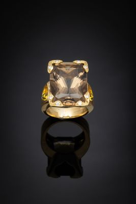 une bague en or jaune sertie d'un quartz carré à facettes sur un fond noir