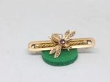yellow gold bee hair clip on a green base with a diamond center