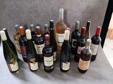 Des bouteilles de vin sont alignées sur une table devant un fond gris.