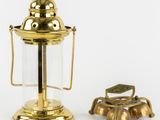 an antique brass oil lamp with a glass cover and a brass bell