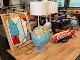 une table sur laquelle se trouvent une lampe, un globe terrestre et un tableau