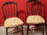 three chairs with upholstered upholstered seats against a red wall