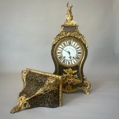 une horloge en or posée sur une table, à côté d'un livre