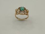 gros plan d'une bague en or avec une pierre verte