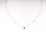 a gold necklace with a blue stone on a mannequin neck