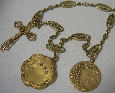 deux colliers en or avec une croix et un médaillon suspendus à une chaîne
