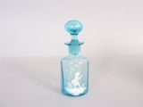 une petite bouteille en verre bleue sur laquelle est représentée une femme
