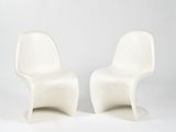 deux chaises en plastique blanches placées l'une à côté de l'autre sur une surface blanche