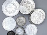 six types différents de pièces d'argent sur une surface grise