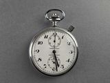 a silver pocket watch on a gray surface