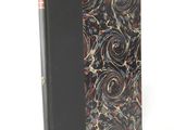 an old book with a black cover and a red and gold swirl design