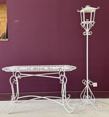 une table en fer forgé blanc et une lampe sur le trottoir